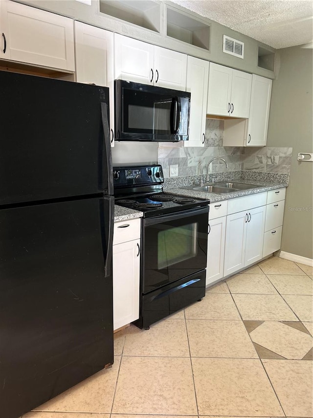 kitchen with a textured ceiling, light tile patterned floors, black appliances, white cabinetry, and sink