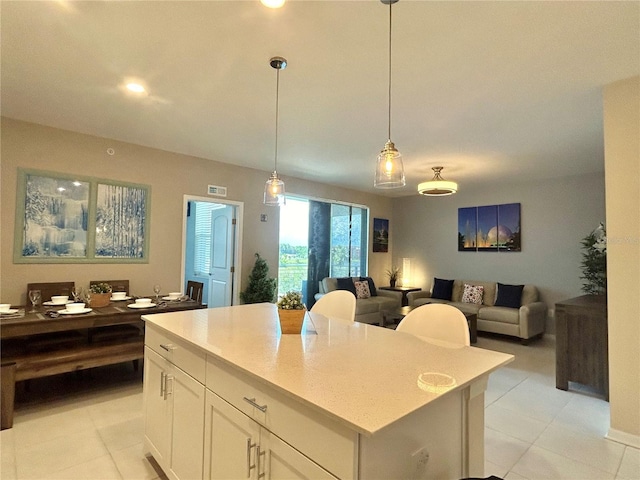 kitchen with decorative light fixtures, white cabinets, light tile patterned floors, and a kitchen island