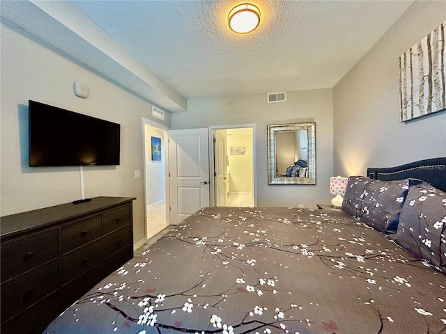 bedroom with a textured ceiling and ensuite bath