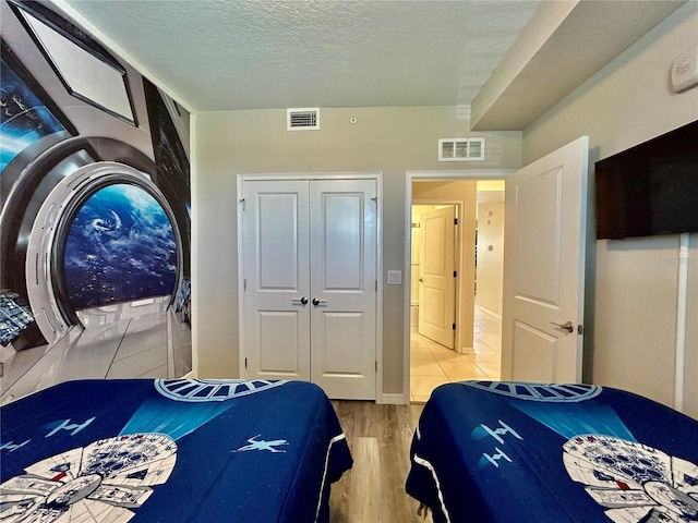 bedroom with a closet, hardwood / wood-style flooring, and a textured ceiling