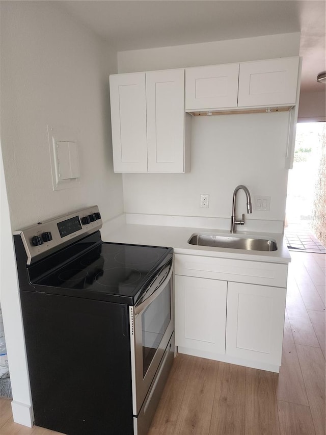 kitchen featuring electric stove, light hardwood / wood-style floors, sink, and white cabinets