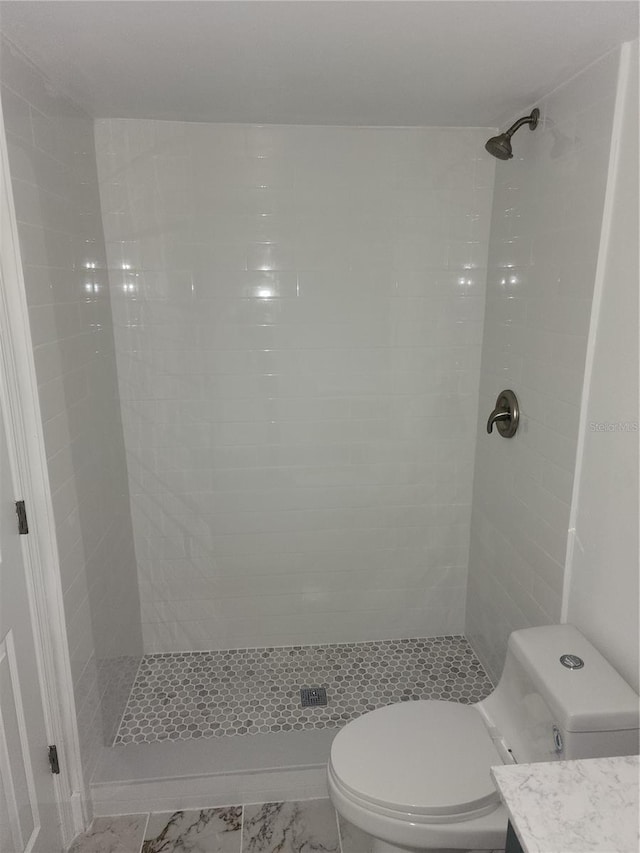 bathroom with vanity, tiled shower, and toilet