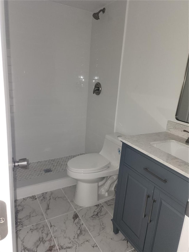 bathroom with vanity, a tile shower, and toilet