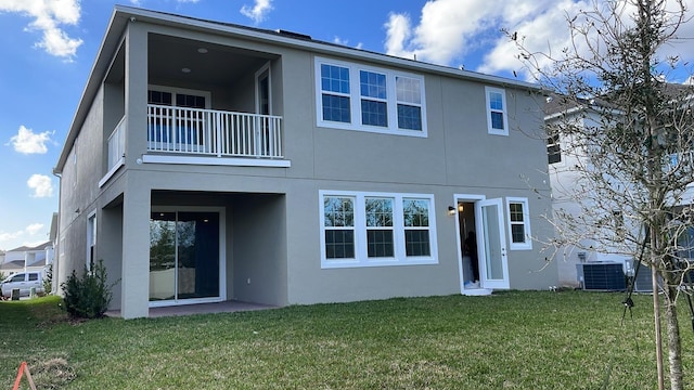 back of house featuring a balcony, central AC, and a yard