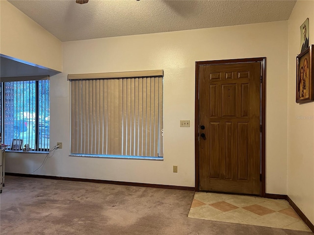 foyer entrance featuring a textured ceiling, ceiling fan, and light carpet