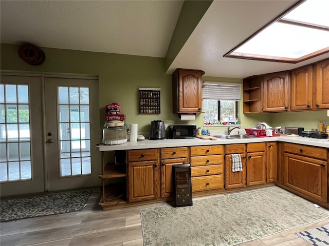 kitchen featuring sink, french doors, light wood-type flooring, and vaulted ceiling