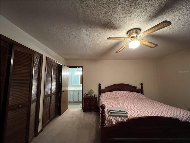 bedroom featuring ensuite bath, a textured ceiling, two closets, carpet, and ceiling fan