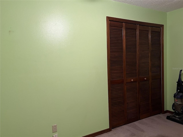 unfurnished bedroom featuring a closet, light carpet, and a textured ceiling