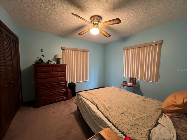 carpeted bedroom with a textured ceiling, ceiling fan, and a closet