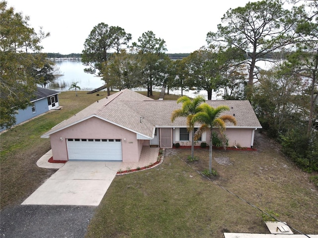 view of front of property with a front yard, a garage, and a water view