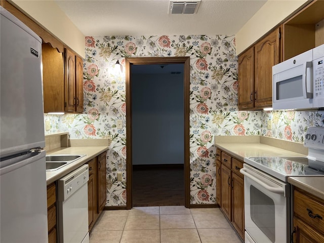 kitchen with light tile patterned floors, sink, and white appliances