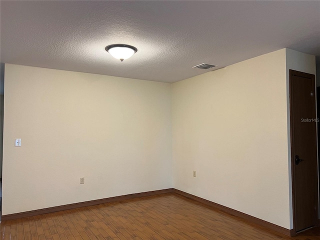 spare room with a textured ceiling and hardwood / wood-style flooring