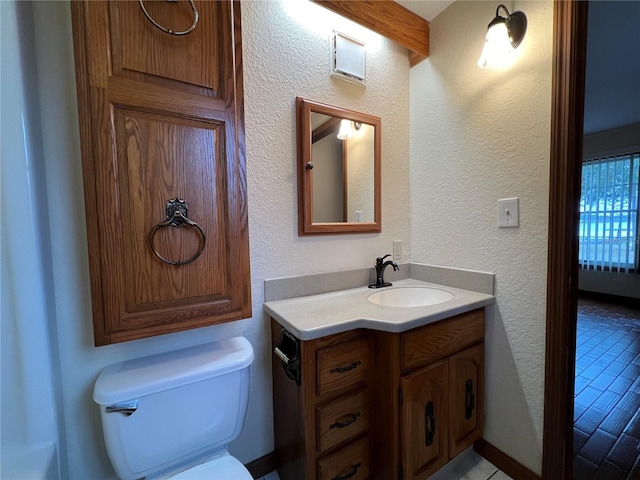 bathroom featuring beam ceiling, vanity, tile patterned floors, and toilet