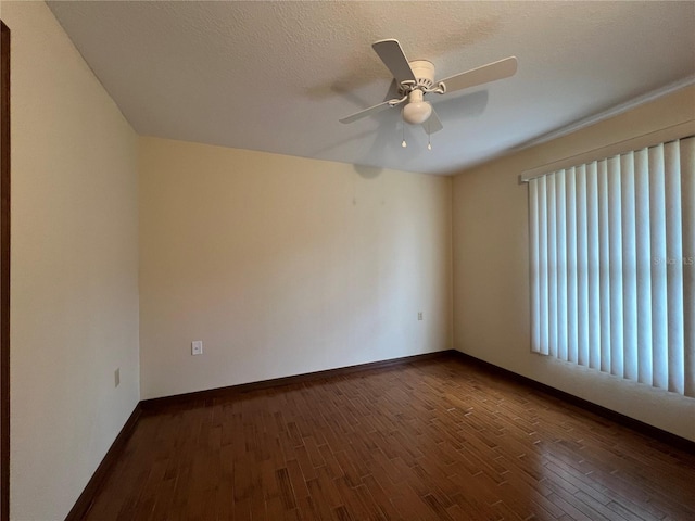 empty room with a textured ceiling, ceiling fan, and dark hardwood / wood-style flooring