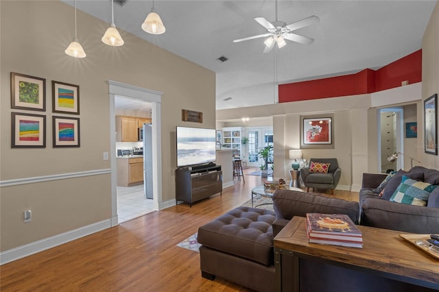 living room featuring lofted ceiling, ceiling fan, and light wood-type flooring