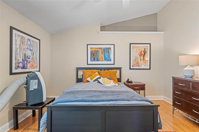 bedroom featuring lofted ceiling, a textured ceiling, ceiling fan, and light hardwood / wood-style flooring