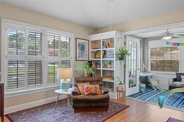 sitting room featuring ceiling fan, wood-type flooring, and a textured ceiling