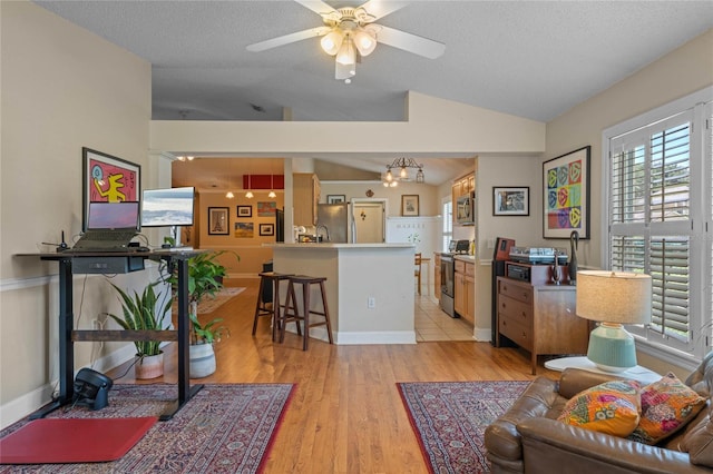 living room with vaulted ceiling, a textured ceiling, and light wood-type flooring