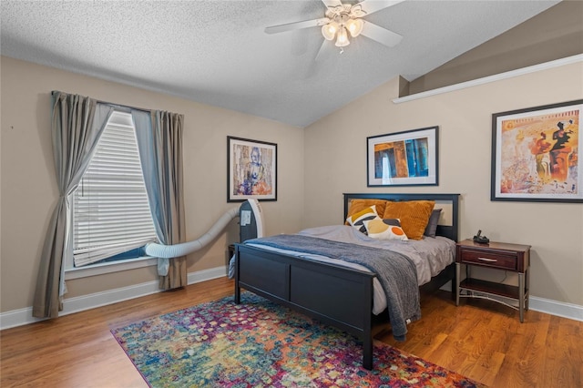 bedroom with ceiling fan, lofted ceiling, light hardwood / wood-style floors, and a textured ceiling