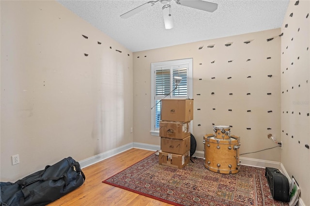 living area with hardwood / wood-style flooring, ceiling fan, and a textured ceiling