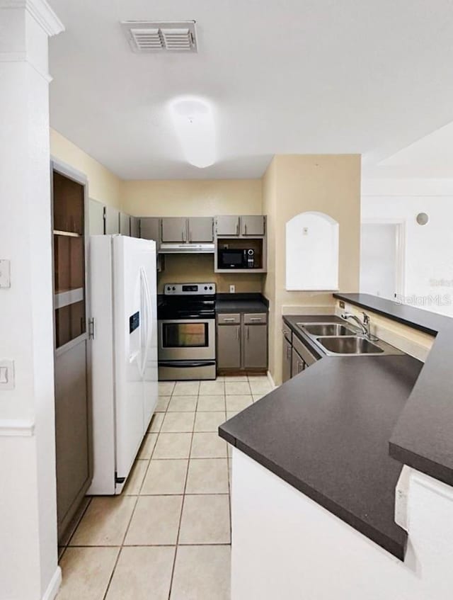 kitchen with white refrigerator with ice dispenser, sink, stainless steel range with electric stovetop, light tile patterned floors, and gray cabinetry