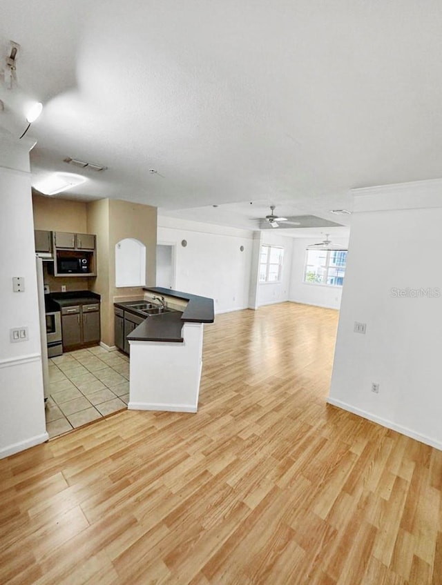 kitchen featuring ceiling fan, sink, stainless steel electric stove, and light hardwood / wood-style flooring