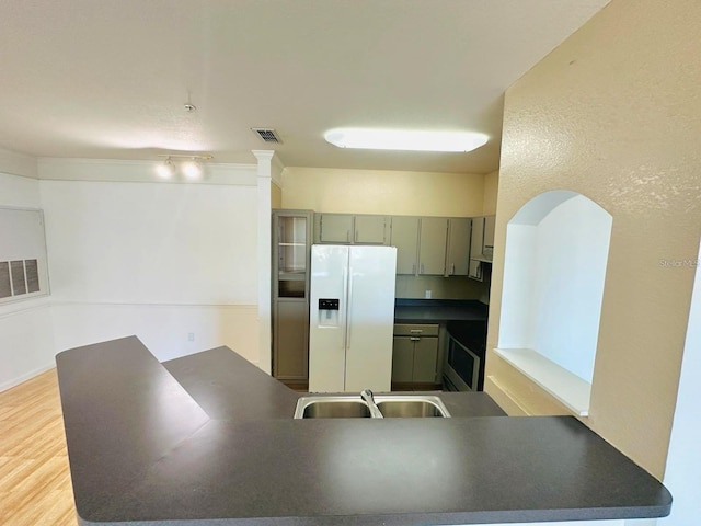 kitchen featuring stove, kitchen peninsula, sink, light hardwood / wood-style flooring, and white fridge with ice dispenser