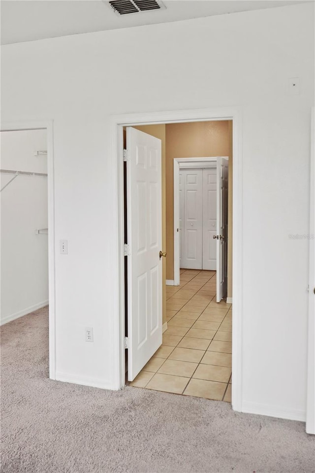 unfurnished bedroom with light carpet, a closet, and a spacious closet