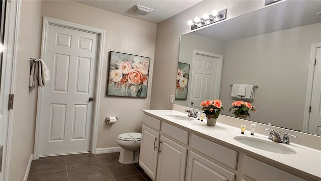 bathroom with a textured ceiling, tile patterned flooring, vanity, and toilet