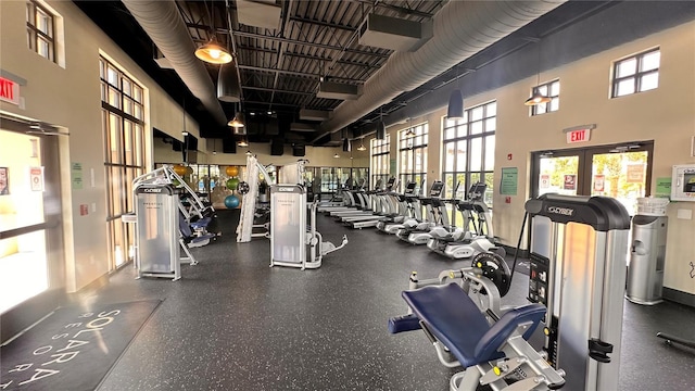 gym featuring a towering ceiling and a healthy amount of sunlight