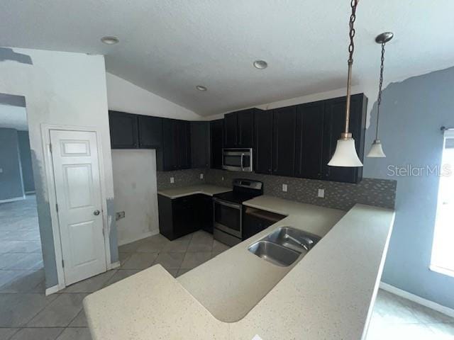 kitchen with lofted ceiling, decorative light fixtures, stainless steel appliances, sink, and kitchen peninsula