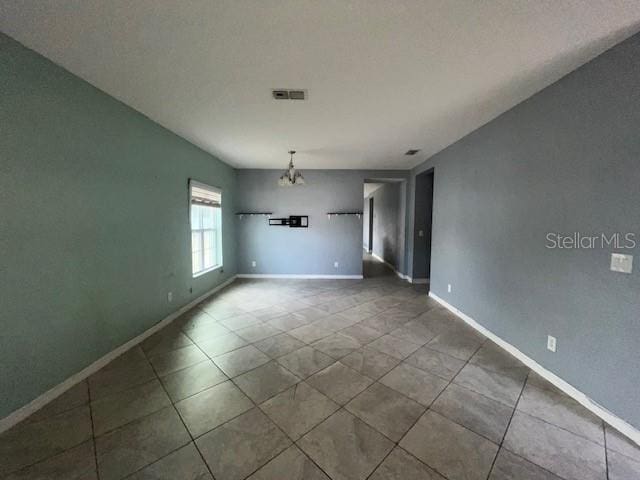 unfurnished room with a notable chandelier