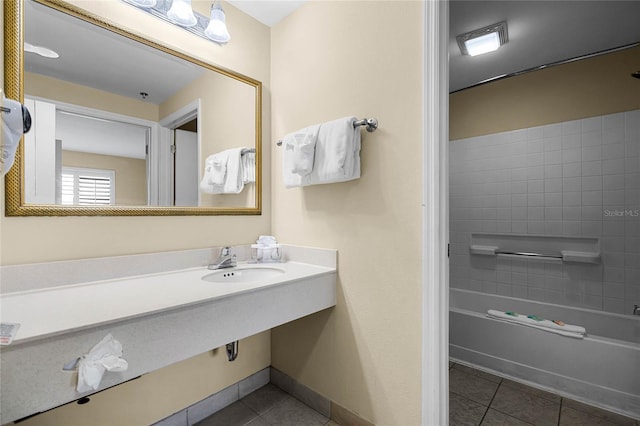 bathroom with tile patterned flooring, tiled shower / bath combo, and sink