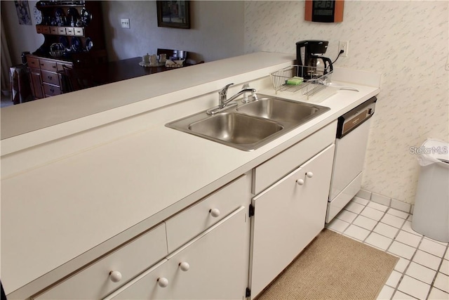 kitchen featuring light tile patterned floors, dishwasher, sink, and white cabinetry