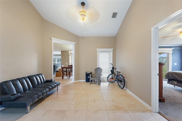 living room featuring ceiling fan, light tile patterned floors, and lofted ceiling