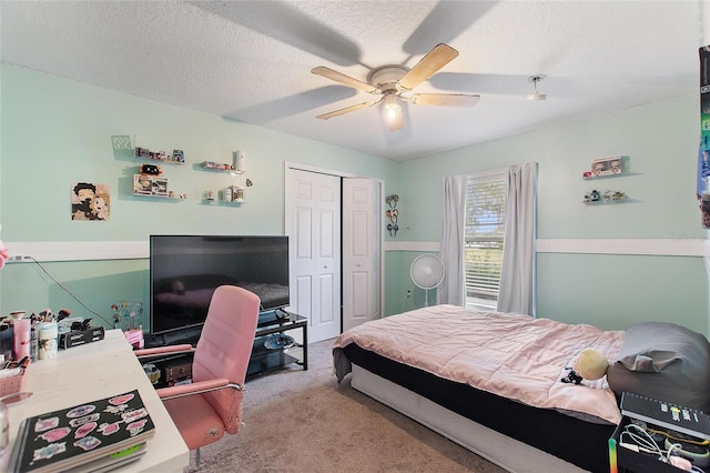 carpeted bedroom with a textured ceiling, ceiling fan, and a closet