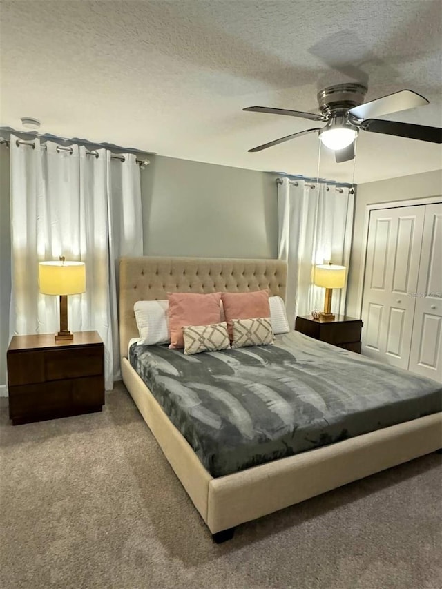 bedroom with a textured ceiling, ceiling fan, carpet flooring, and a closet