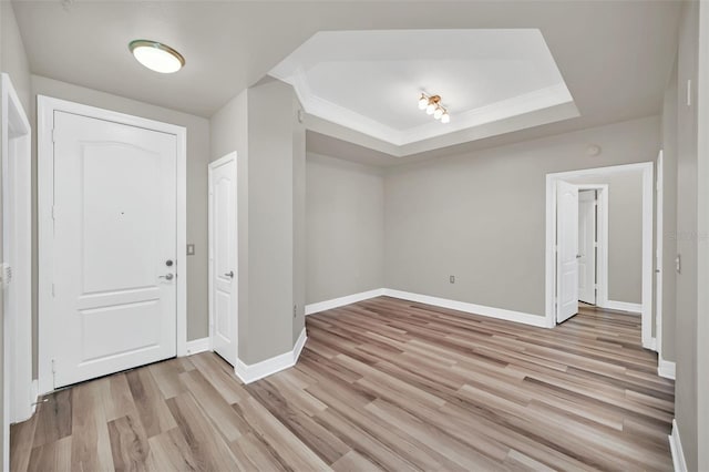 entryway featuring a tray ceiling, light hardwood / wood-style flooring, and crown molding