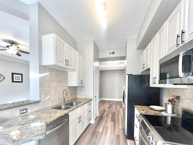 kitchen featuring light stone countertops, white cabinets, stainless steel appliances, sink, and ceiling fan