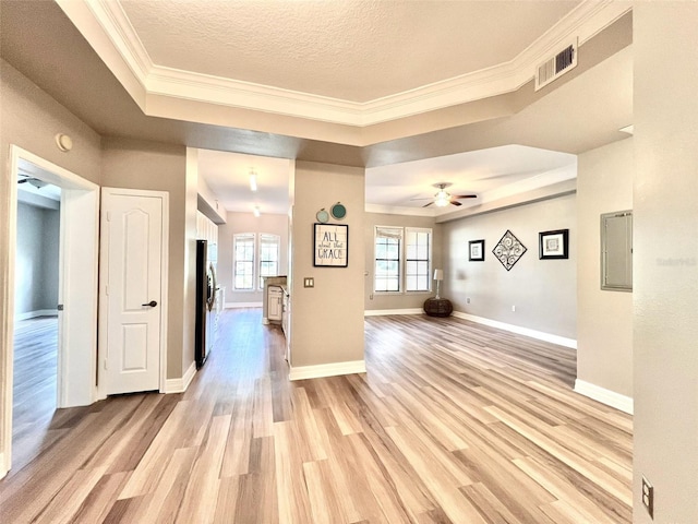 interior space featuring a textured ceiling, ceiling fan, light hardwood / wood-style floors, and a tray ceiling