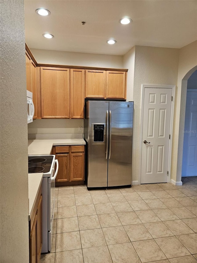 kitchen with stainless steel fridge with ice dispenser, light tile patterned floors, and range with electric stovetop