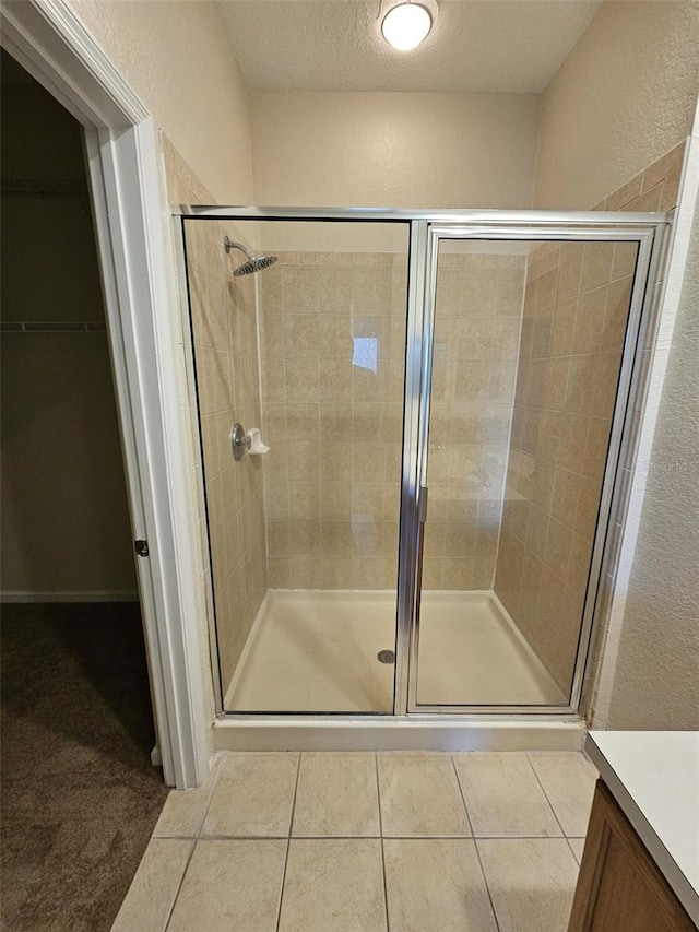 bathroom with a textured ceiling, tile patterned floors, and a shower with door