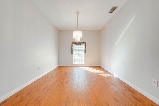 unfurnished room with a chandelier and light hardwood / wood-style flooring