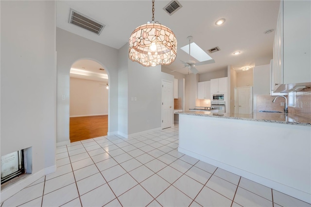 kitchen featuring stainless steel microwave, white cabinetry, ceiling fan with notable chandelier, and sink