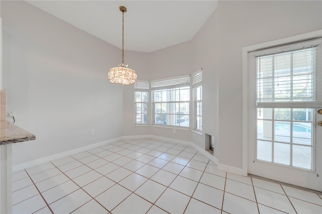 unfurnished dining area featuring light tile patterned floors, vaulted ceiling, a notable chandelier, and a wealth of natural light