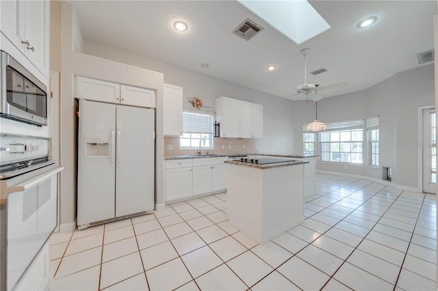 kitchen featuring white appliances, white cabinetry, a skylight, tasteful backsplash, and sink