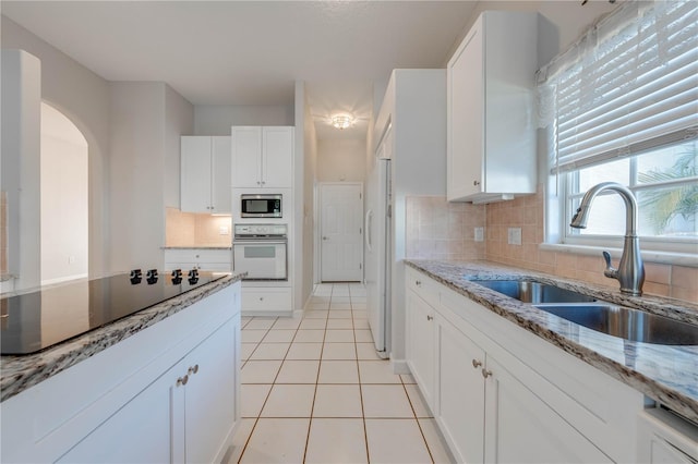 kitchen featuring decorative backsplash, sink, white appliances, and white cabinets