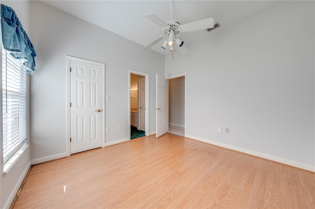 unfurnished bedroom featuring ceiling fan, ensuite bath, vaulted ceiling, and light hardwood / wood-style floors