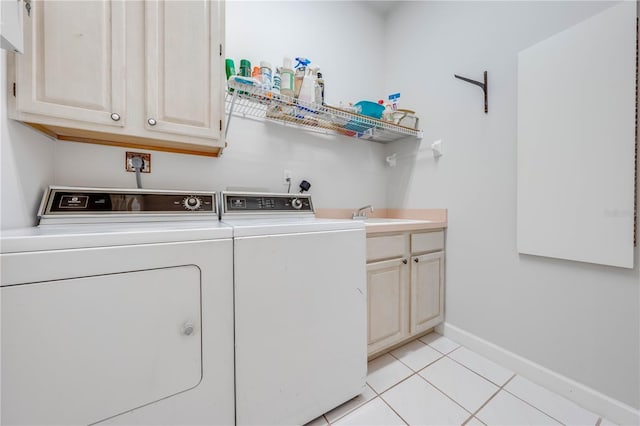 clothes washing area with light tile patterned floors, sink, washing machine and clothes dryer, and cabinets