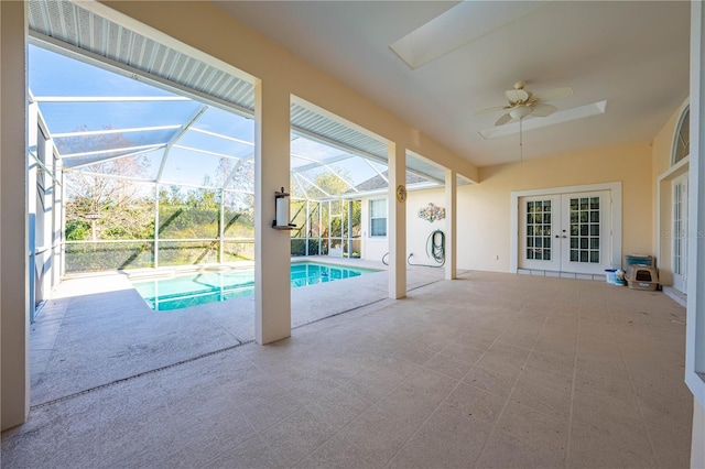 view of swimming pool with ceiling fan, a patio area, a mountain view, glass enclosure, and french doors